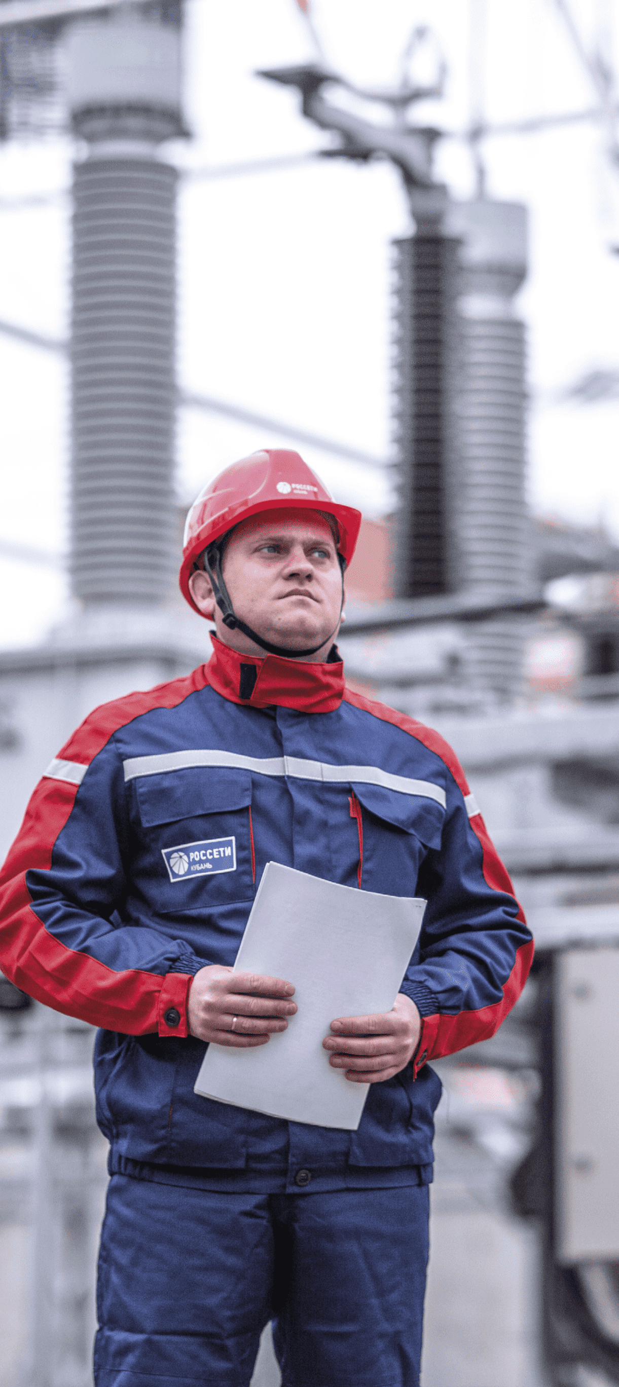 A worker in a hard hat with documents in A4 sheets on the background of a power plant